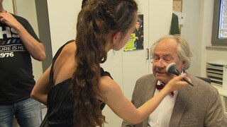 Schauspieler Hartmut Volle wird am Set von einer Maskenbildnerin geschminkt