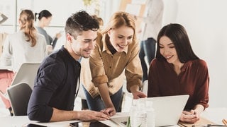 Frau erklärt KollegInnen etwas am Computer
