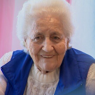 Die 90-jährige Sofia in der Wohnküche in der Pflege-WG in Stuttgart. Sie lauscht der Unterhaltung ihrer Mitbewohner und lächelt. 