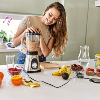 Frau püriert Obst mit Standmixer