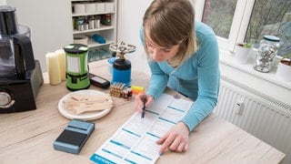Stromausfall: Mit Hilfe einer Checkliste prüft eine Frau, was man im Notfall an Vorräten zuhause haben sollte.