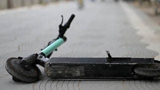 Ein E-Scooter liegt auf einer Straße.