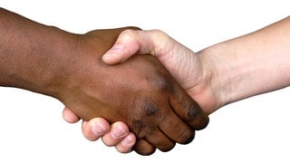 Handschlag einer schwarzen und einer weißen Hand: Menschenrassen gibt es nicht