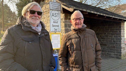 Peter Thomas (links) und Ernst-Willi Giersen stehen an der Bushaltestelle in Ockenfels