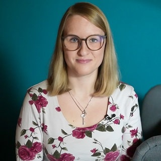 Magdalena Hoffmann, eine junge Frau, sitzt auf einem Sessel und schaut in die Kamera.
