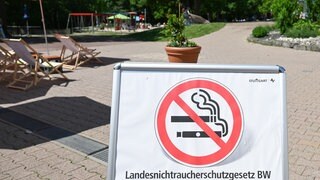 Ein Hinweisschild mit Rauchverbot-Symbol informiert in einem Freibad über das «Landesnichtraucherschutzgesetz BW» und ein Rauchverbot auf dem Gelände.