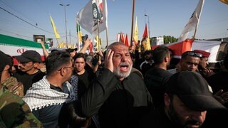 Trauernde tragen Särge, die mit der iranischen Fahne (l) und der irakischen Fahne (r) bedeckt sind, während einer Beerdigung für Kämpfer der «Popular Mobilization Forces», die bei Luftangriffen auf Stützpunkte ums Leben gekommen sind.