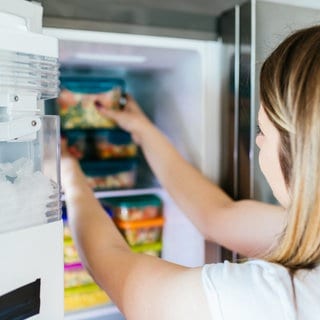 Frau sortiert Gefrierschrank