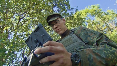 Junger Soldat in Felduniform steuert eine Drohne