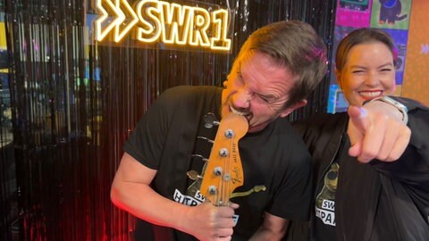 Cora Klausnitzer und Ingo Lege sind im Studio und zeigen in die Kamera bei der SWR1 Hitparade.