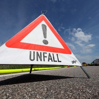 Ein Warndreieck mit der Aufschrift "Unfall" steht auf einer Autobahn (Symbolbild)
