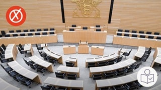 Der Sitzungs·saal des Land·tags von Baden-Württemberg. Man sieht leere Stühle in einem Halb·kreis. An der Wand das Wappen von Baden-Württemberg. Links oben ein weißes Kreuz auf rotem Hintergrund. Rechts unten das SWR-Logo für Leichte Sprache. 