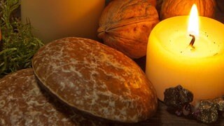 Wundervolles Winterwissen - der SWR1 Adventskalender: Warum isst man Lebkuchen nur zu Weihnachten? Das Bild zeigt Lebkuchen, dahinter Nüsse, Gewürze, Tannenzweige und zwei brennende Kerzen