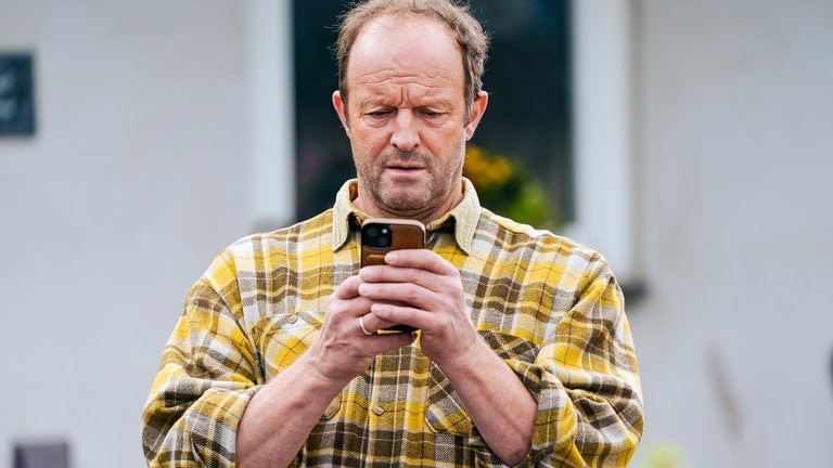 Bernd (Martin Wangler) sieht auf sein Handy