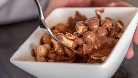 Schoko-Wibele werden mit einer Gabel unter die geschmolzene Schokolade gehoben