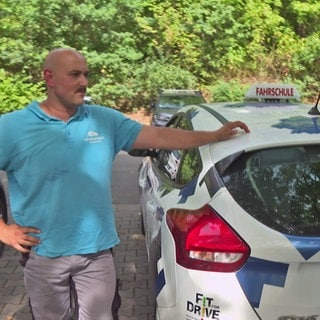 Fahrschüler mit Fahrlehrer am Fahrschulauto