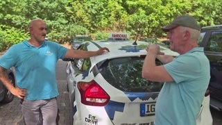 Fahrschüler mit Fahrlehrer am Fahrschulauto