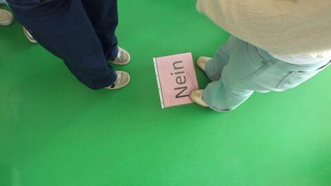 Die Schülerinnen und Schüler einer 10. Klasse der Comenius Ganztagsrealschule an der Merkur Akademie in Karlsruhe stehen am Schild, auf dem "Nein" steht.