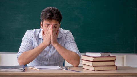Gestresster Lehrer vor einer Schultafel | Warum viele Lehrkräfte den Beruf wechseln wollen