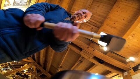 Froschperspektive aus Sicht der Prägestation auf Rainer Pfennig, der einen Hammer vorsichtig niedersausen lässt.