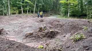 Revierleiter Tobias Helfenstein (links) vor einer Mulde, die künftig bei Starkregen das Wasser im Wald bei Kirn-Sulzbach auffangen soll. 