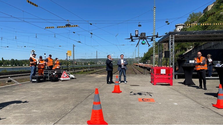 Eine Drohne fliegt am Bahnhof in Koblenz-Ehrenbreitstein in der Luft über die Gleise. 