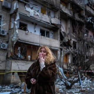 Eine Frau neben ihrem Haus in Kiew in der Ukraine nach einem Raketenangriff. Russland hat am 24. Februar 2022 einen umfassenden Angriff auf die Ukraine gestartet und Städte und Stützpunkte mit Luftangriffen oder Granaten beschossen.