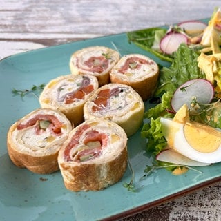 Gefüllte Crêperöllchen auf Salat mit Ei