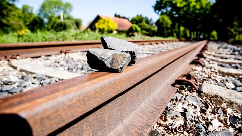 Zwei Steine liegen auf Bahnschienen. (Symbolbild)