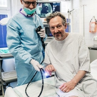 Gute Laune vor der Darmspiegelung! Prof. Straßburg (l.) wird mit diesem Endoskop an der Uniklinik Bonn gleich den Darm von Eckart von Hirschhausen durchleuchten. Die Dokumentation "Hirschhausen und der Darm" ist in der ARD Mediathek abrufbar.