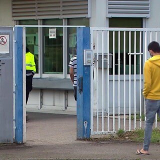 Zwei Männer laufen durch ein Tor der "Kurpfalz-Kaserne"