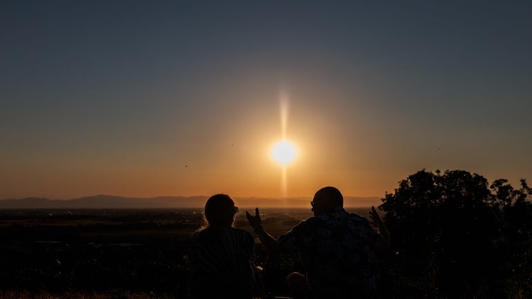 Menschen sitzen auf dem Batzenberg und sehen sich die partielle Sonnenfinsternis an. Wenn am Abend die partielle Sonnenfinsternis über Deutschland zu sehen ist, herrschen zu dieser Zeit fast überall auch optimale Wetterbedingungen, um sie zu beobachten, hieß es vom Deutschen Wetterdienst.
