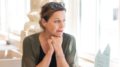 Jule Ronstedt im Interview: Die Schauspielerin stützt nachdenklich das Kinn auf die Hände und schaut aus dem Fenster.