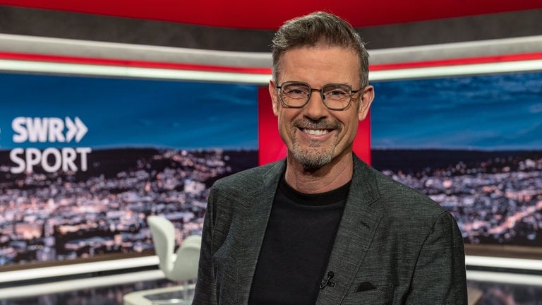 SWR Sport-Moderator Michael Antwerpes in der SWR Sport-Studiodekoration mit dem SchriftzugLogo SWR Sport