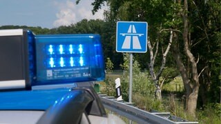 Polizeiauto steht vor Autobahnschild - Polizei stoppt illegales Autorennen auf A63.