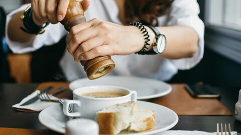 Frau würzt Suppe mit Pfeffer