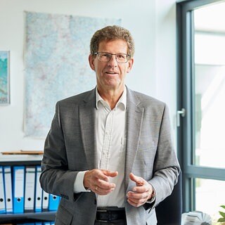Klima-Experte Volker Kienzlen steht in einem Büro, im Hintergrund sind Aktenordner. Wie kann kommunaler Klimaschutz aussehen? Welche Möglichkeiten der Energieeinsparung habe ich? Was kosten konkrete Klimaschutzprojekte die Gemeinden? Fragen an Dr. Volker Kienzlen, den Geschäftsführer der Klimaschutz- und Energieagentur BW, in SWR1 Leute.