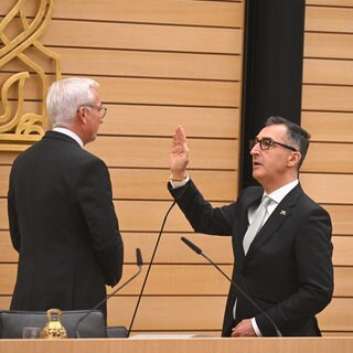 Ministerpräsident Cem Özdemir hebt die rechte Hand zum Amtseid vor Landtagspräsident Thomas Strobl.