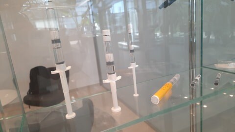 In einer Glasvitrine präsentiert die Firma Vetter Pharma einige seiner Produkte wie mit Arzneimitteln befüllte Spritzen. 