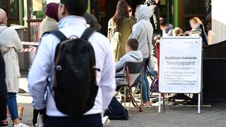 Menschen warten schon Stunden vor der Öffnung vor dem Eingang der Stuttgarter Ausländerbehörde. Nach Baden-Württemberg kommen weniger Flüchtlinge.