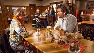 Evelyn und Markus Riedle sitzen im Löwen und unterhalten sich, im Hintergrund sieht man die Stammtischler, die die beiden beobachten