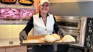 Bäckerin Manuela Lingenhöle steht zwischen Verkaufstresen und  ihrem Ofen. In dem backt sie ganz alleine im Neu-Ulmer Donaucenter ofenwarme Brezeln, Seelen und Brötchen.