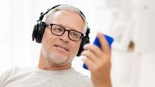 Mann mit Smartphone und Kopfhörern - so hält der Akku des Handys länger