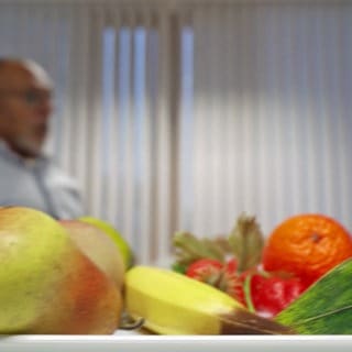 Ein Teller mit Obst im Vordergrund, in Hintergrund ein Mann und eine Frau