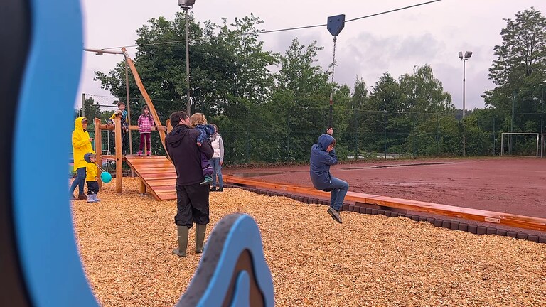 Ein Kind schwingt sich mit einer Seilbahn über den Spielplatz: Der Unisport der Rheinland-Pfälzischen Technischen Universität Kaiserslautern-Landau (RPTU) hat auf dem Campus einen Abenteuerspielplatz eröffnet. Das Kitz-Land können Kinder mit einer Unisport-Karte besuchen.