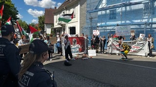 Polizeibeamte beobachten eine Demonstration von Pro-Palästina-Aktivisten unweit der Langenauer Martinskirche. Bei einer Hausdurchsuchung bei dem Organisator der Proteste ist ein Beweismittel sichergestellt worden.