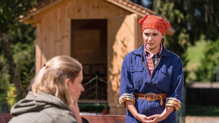 Jenny spricht mit Celine, im Hintergrund das Hühnerhaus