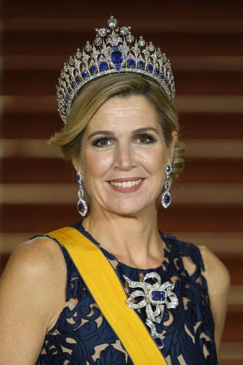 Königin Maxima mit einer Tiara und dunkelblauem Kleid lächelt in die Kamera.