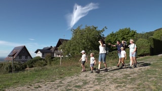 Eine Gruppe Menschen wandert über eine Bergkuppe bei Sasbachwalden.