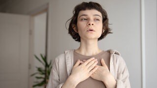 Eine Frau atmet durch. Die tiefe Atmung macht das Seufzen gesund und gibt ihm eine Bedeutung für uns.